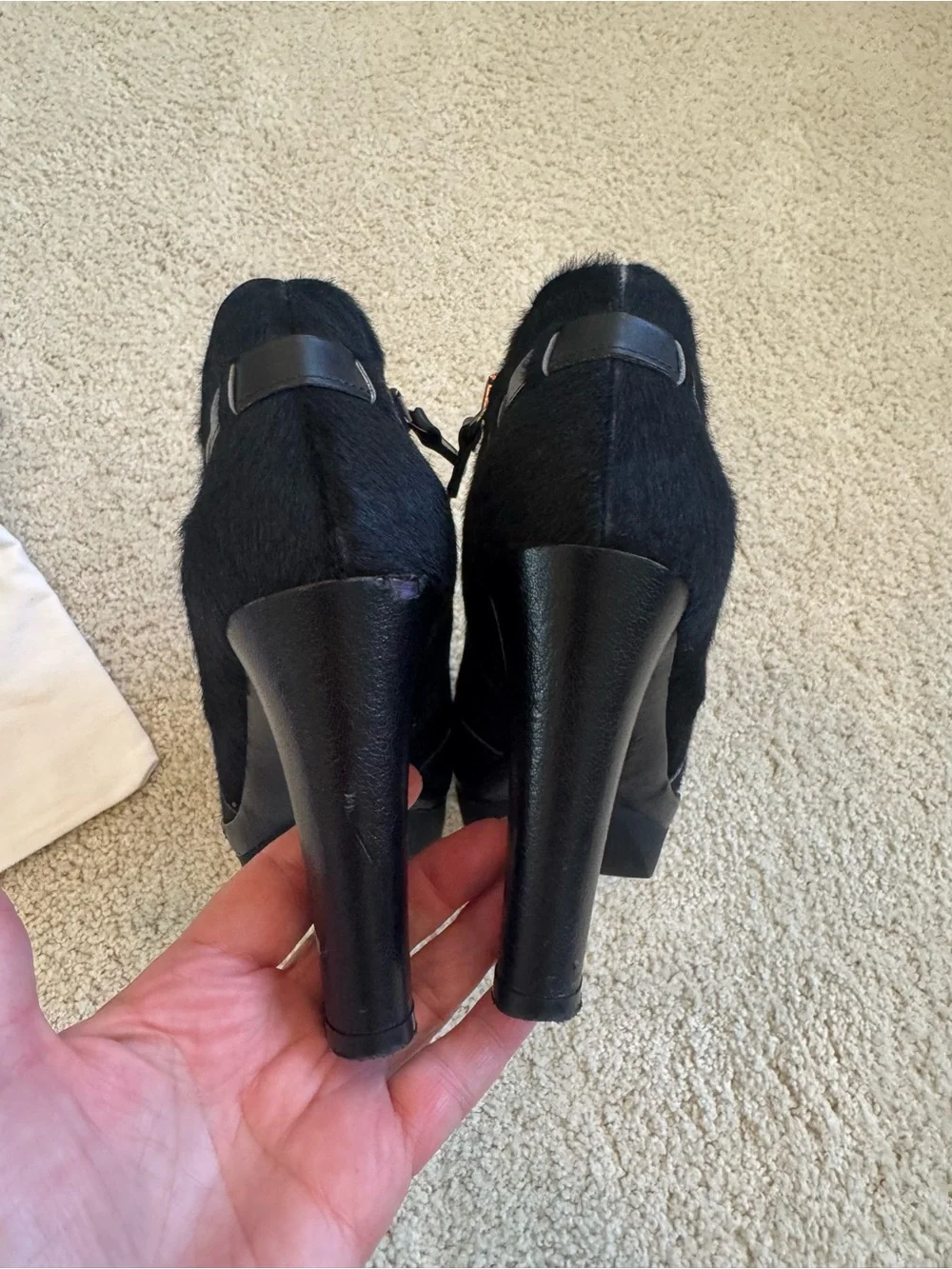 ZORAIDE black calf hair ankle booties with leather strap and tassel accents.